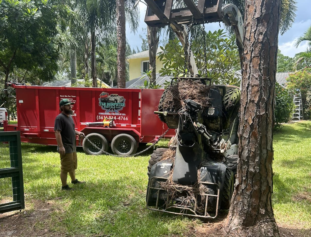 Compact track loader loading yard debris into a red 17-yard dump trailer in Loxahatchee.