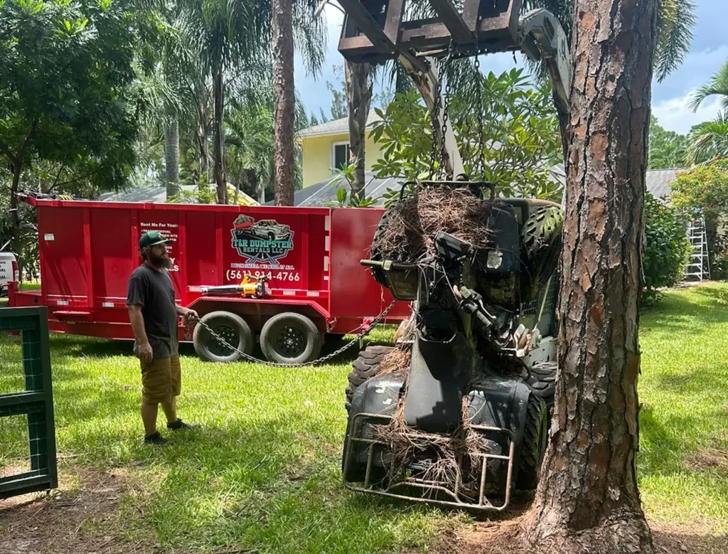 Compact track loader loading yard debris into a red 17-yard dump trailer in Loxahatchee.