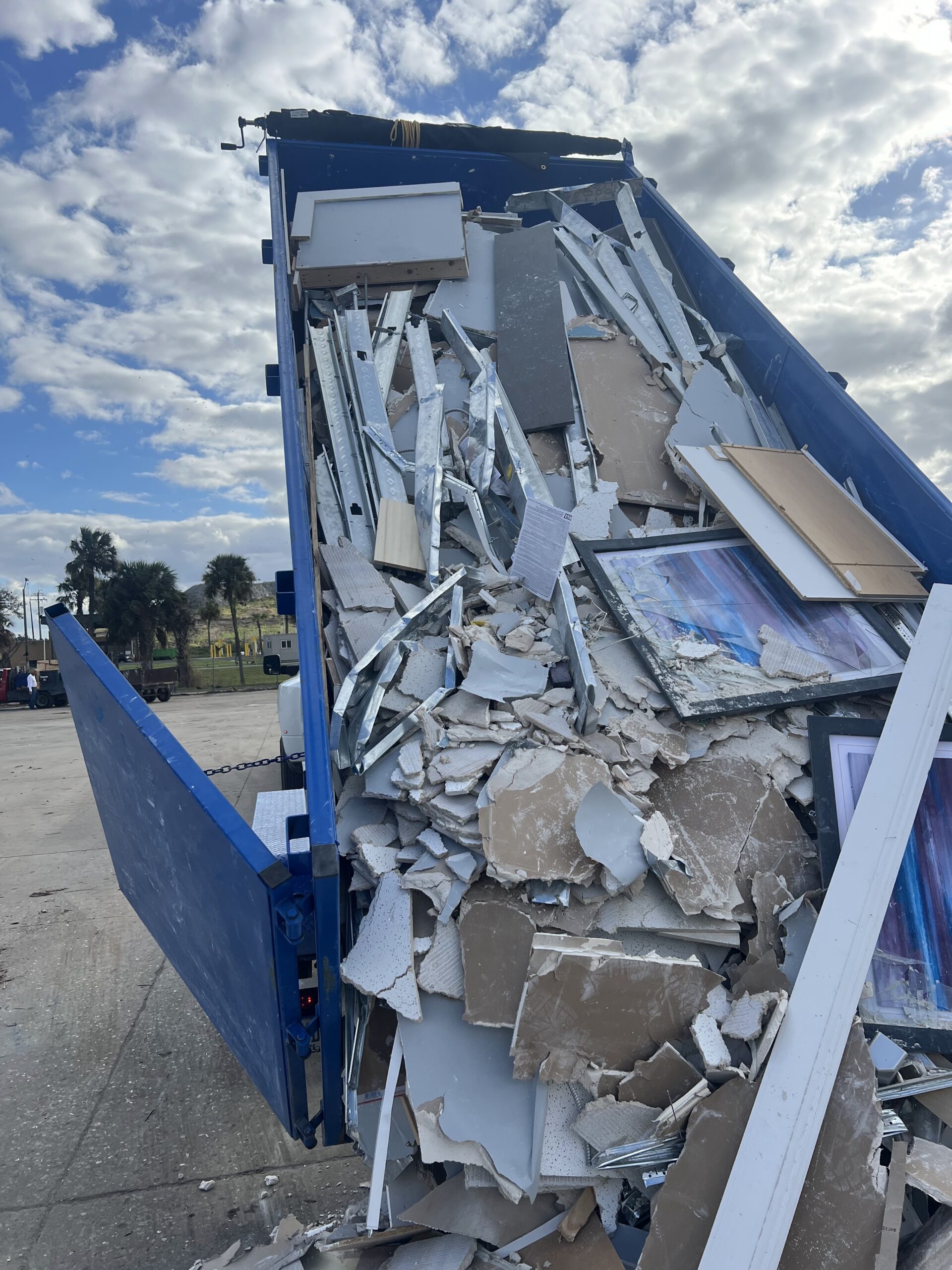 Construction debris being unloaded from a blue 17-yard dump trailer in Palm Beach County, FL.