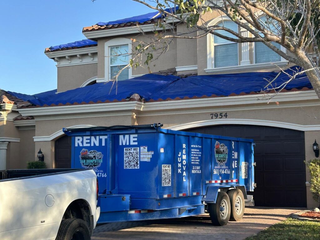 Roof tiles being loaded into a 17-yard dump trailer during a residential roofing project.