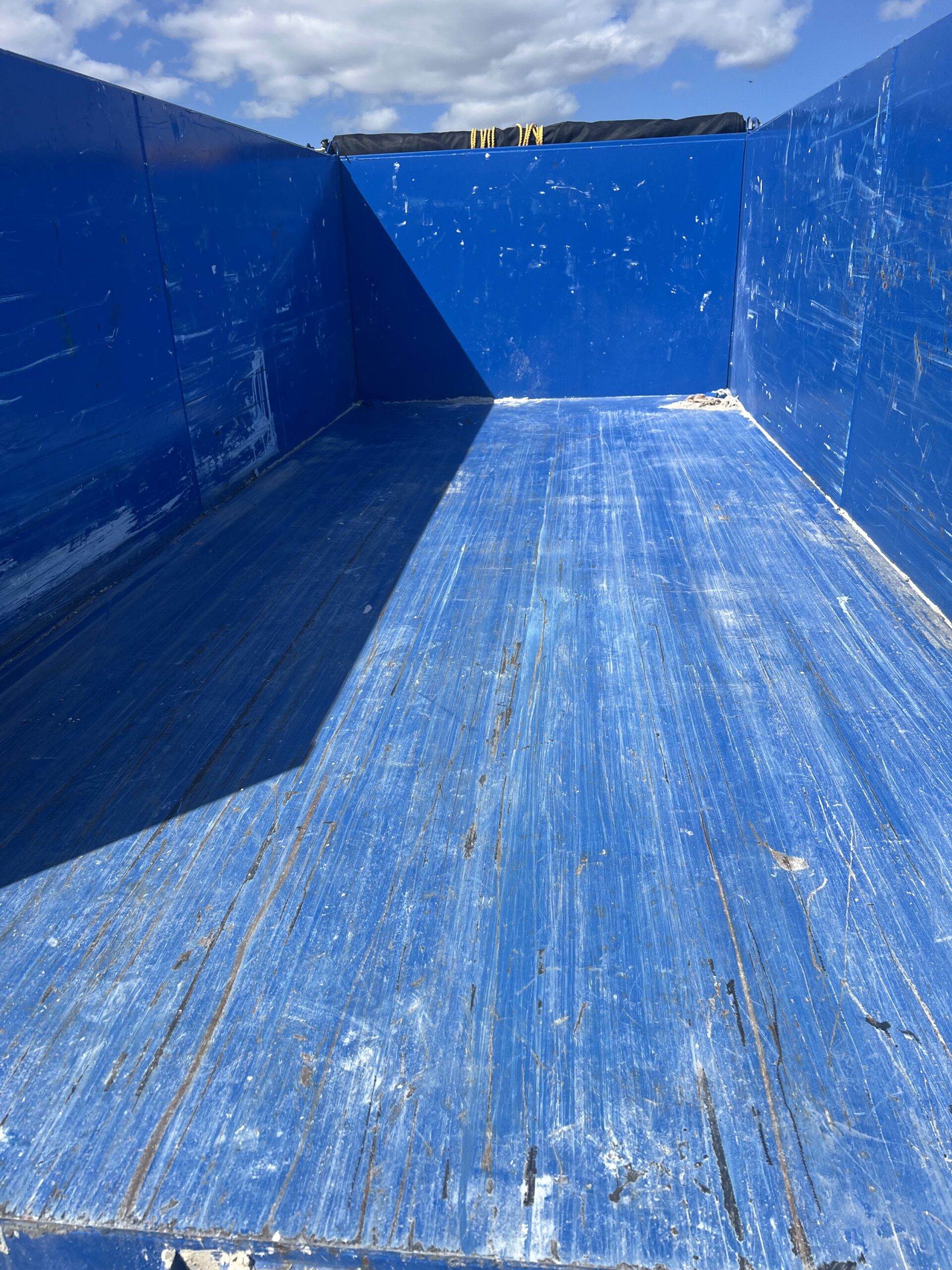 Empty interior of a blue 17-yard dump trailer.